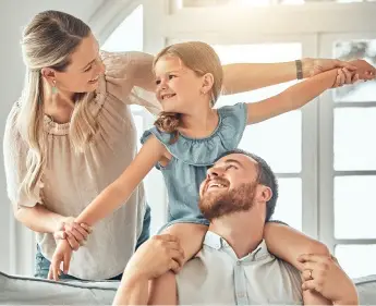 Father with daughter on shoulders smiling at mom
