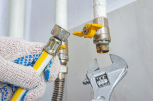 A technician using a wrench on a gas line